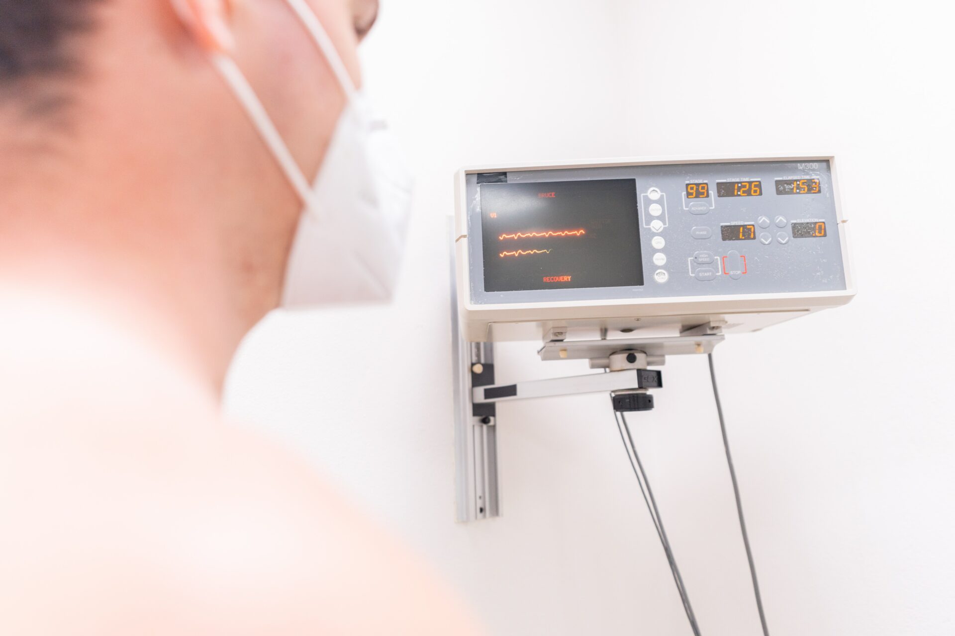 man wearing a face mask looking at a heart monitor